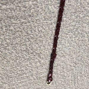 A skinny dark brown leather belt ,  gold buckle